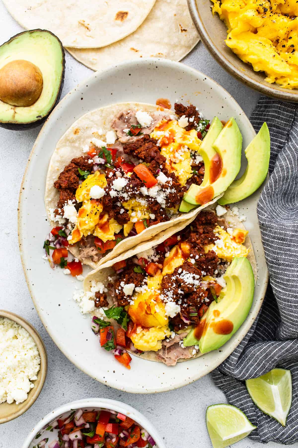 Start your morning off with this breakfast tacos recipe made with perfectly scrambled eggs, beans, breakfast chorizo, and yummy toppings. tacos on plate.