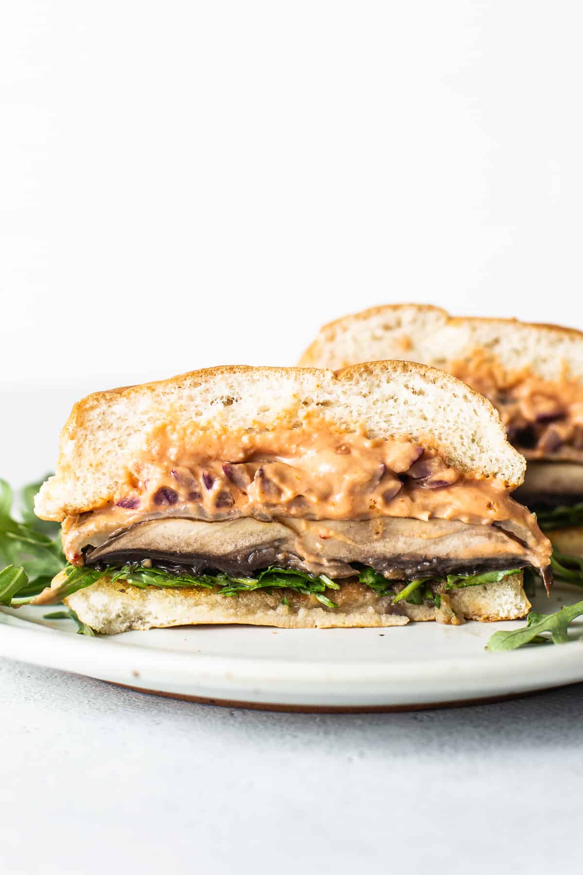 These portobello mushroom burgers are one of the most delicious vegetarian sandwiches you'll ever have! Not only do they look like regular burgers, but they also have a similar texture and flavor. Portobello mushroom burger on a plate.