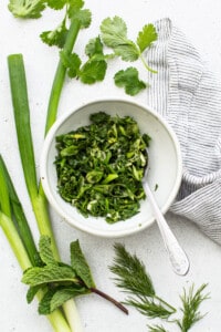 Fresh herbs in a bowl with a spoon.