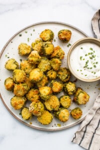A plate of fried zucchini with a dipping sauce.