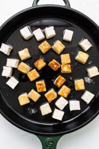Tofu in a skillet on a white surface.