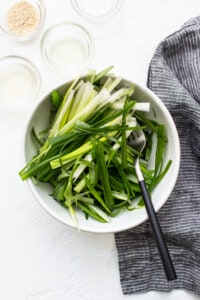A white bowl with green onions and a fork.