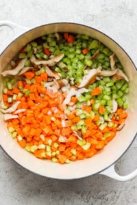 A pot with carrots, celery and mushrooms in it.