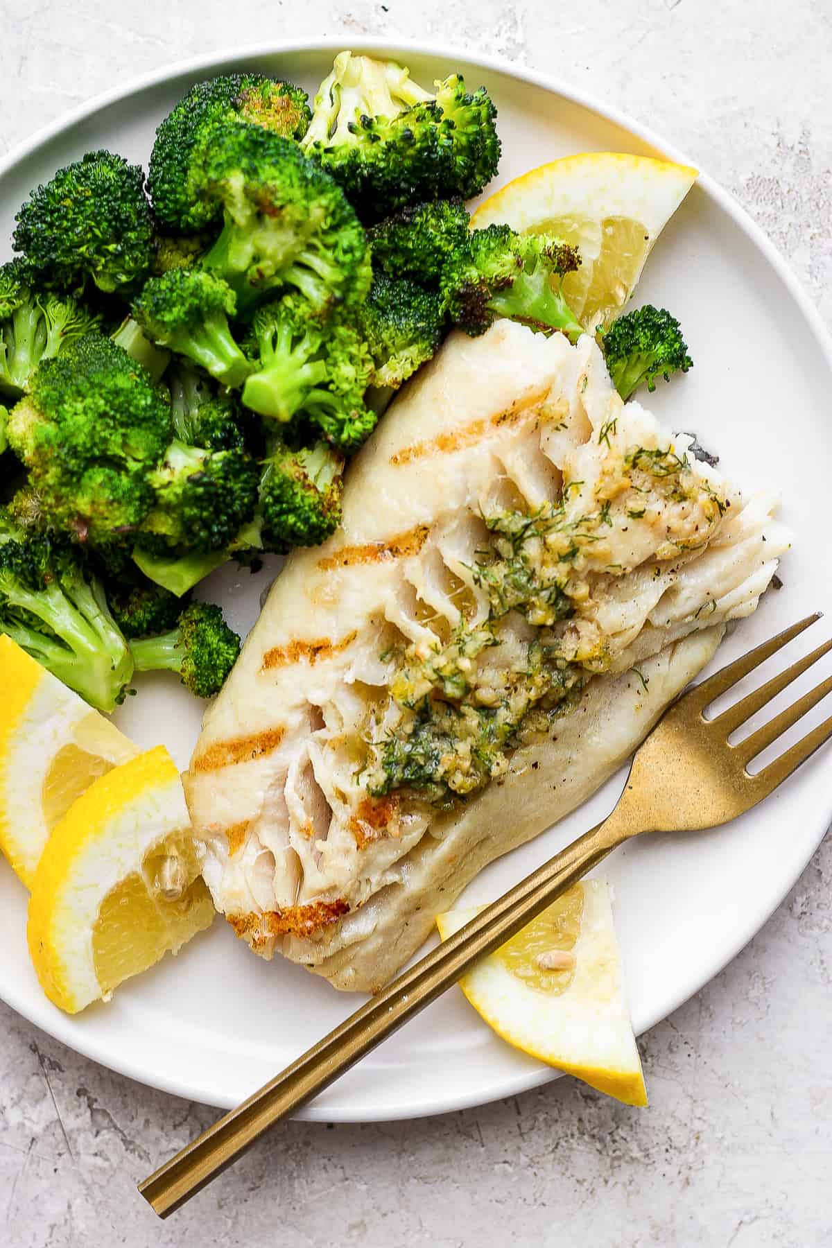 You've got to try this delicious grilled fish recipe! A medley of smoky, savory, and fresh flavor is the perfect way to bring your favorite fish to life. Grilled fish on a plate with broccoli.