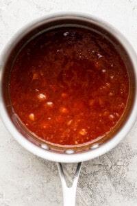 a pot filled with red sauce on top of a counter.