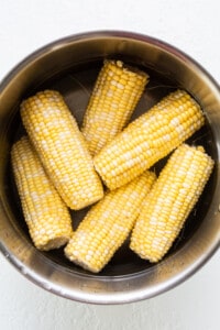 Corn on the cob in a metal bowl.