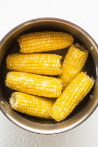 Corn on the cob in a metal bowl.
