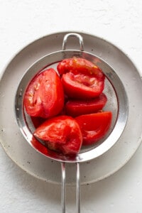 ripe tomatoes in a metal strainer.