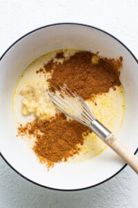 A bowl with cinnamon, sugar, and a whisk.