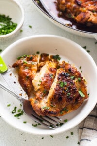 Chicken breast in a white plate with a fork.