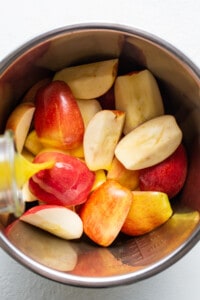 Sliced apples in a bowl with a liquid pouring over them.