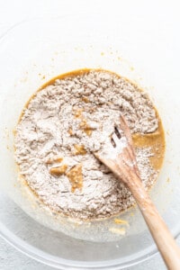 A bowl of flour with a wooden spoon in it.