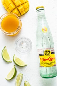 A bottle of water with limes and a slice of lime.