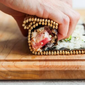 a person making a sandwich on a wooden cutting board.
