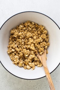 granola in a bowl with a wooden spoon.