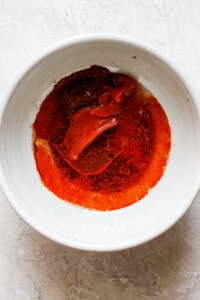 a white bowl with a red sauce in it.