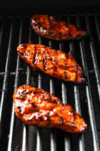 three grilled chicken breasts on a grill.