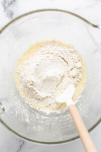 a bowl of flour with a wooden spoon in it.