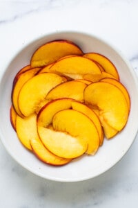sliced peaches in a white bowl.