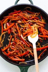 A skillet filled with red peppers and onions.