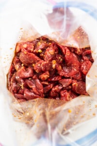 Roasted red peppers in a bag on a white plate.