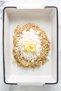 A white baking dish with granola and eggs in it.