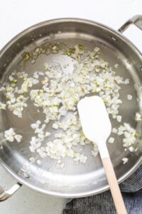 Sauteing onions in a pan with a wooden spatula.