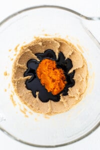 A glass bowl filled with a mixture of peanut butter and orange juice.