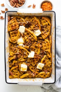 Pumpkin waffles in a baking dish with butter and pecans.