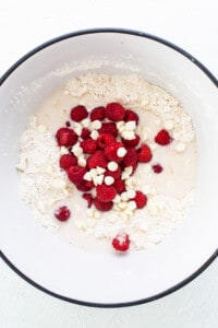 A bowl with raspberries and white chocolate in it.