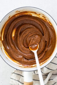 A bowl of peanut butter in a pan with a spoon.
