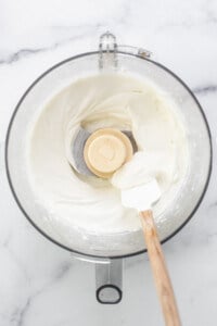 Whipped cream in a mixing bowl with a wooden spoon.