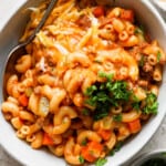 A bowl of macaroni and cheese with meat and vegetables.