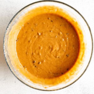 A bowl with a sauce on a white surface.