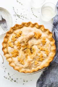 Apple pie on a plate with a glass of milk.