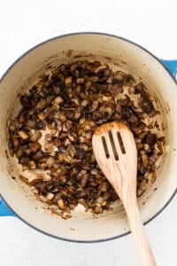 Mushrooms in a pan with a wooden spoon.