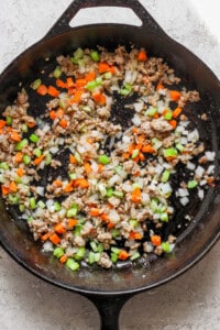 A cast iron skillet filled with meat and vegetables.
