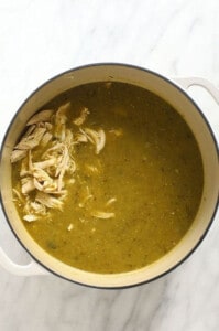 A pot of green chili soup with chicken.