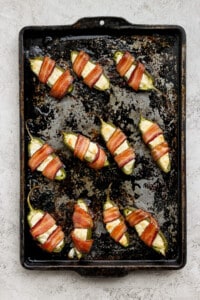 Bacon wrapped jalapenos on a baking sheet.