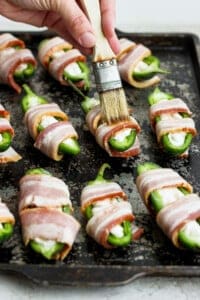 Bacon wrapped jalapenos on a baking sheet.