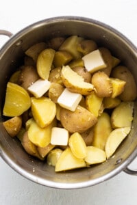 Potatoes and cheese in a pot on a white background.