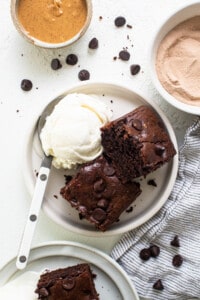 A plate of chocolate brownies with ice cream and whipped cream.