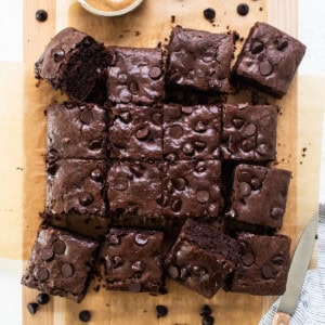 Chocolate brownies on a cutting board with peanut butter.