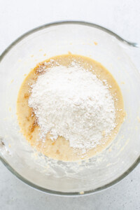 A glass bowl with flour and sugar in it.