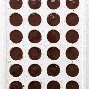 A tray filled with chocolate covered donuts.