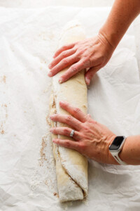 A woman's hands slicing a loaf of bread.
