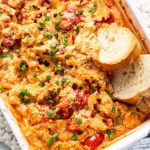A casserole dish with chicken, tomatoes and bread.