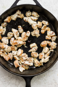 Fried chicken in a skillet on a white surface.