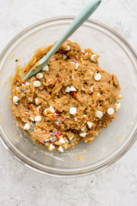 A bowl of cookie dough with sprinkles and a spoon.