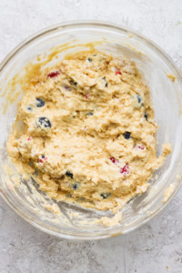 A bowl of dough with blueberries in it.